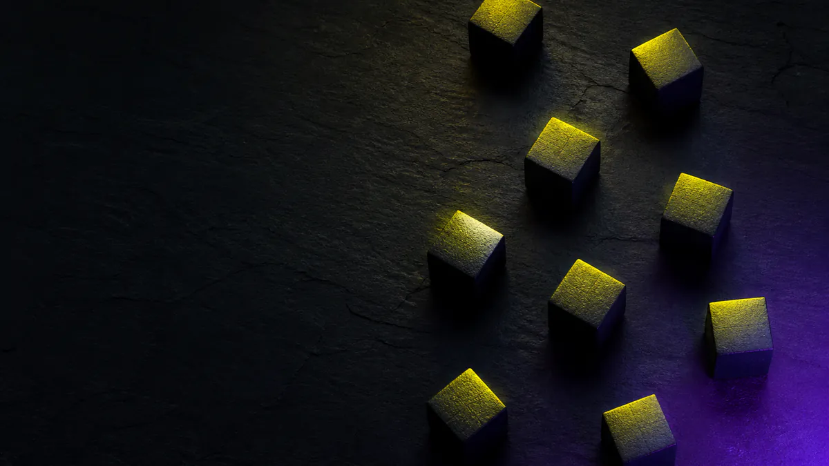 Small cubes lit from one side on dark slate, a stylised image for a story about ChatGPT Ads